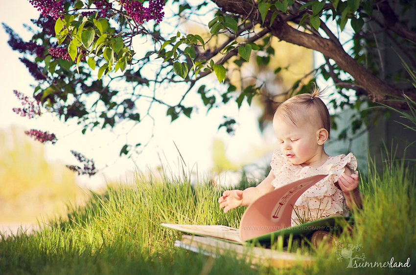 Little girl reading under the lilacs in Kennewick, Wash. by Child photographer Sandy Summers Russell of Summerland Photography.